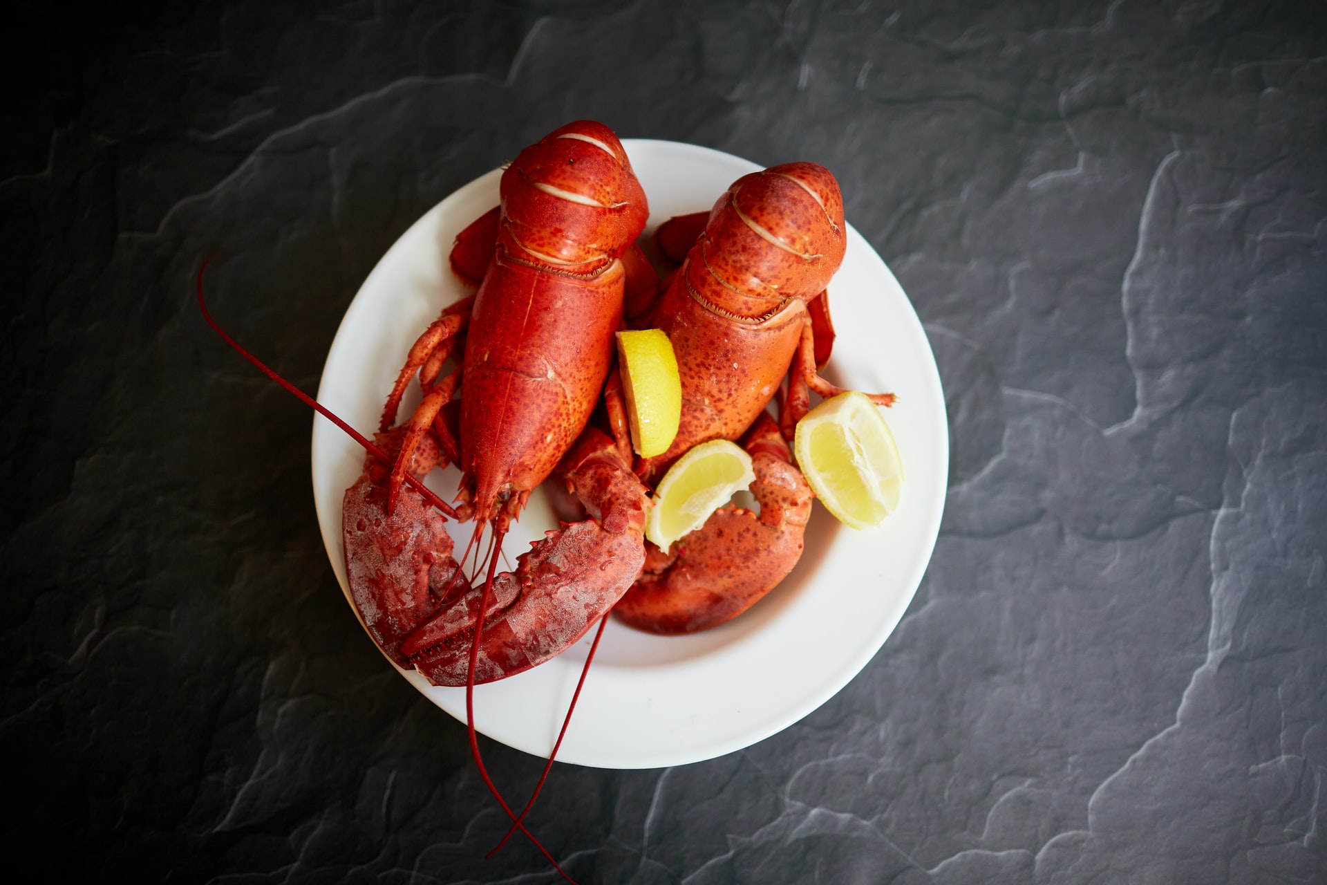 two lobsters with lemon on a plate
